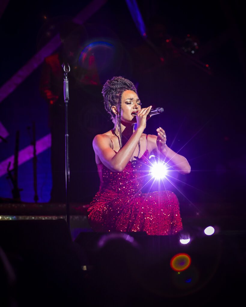 A woman kneels on the stage while singing