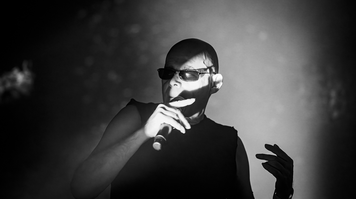 A man sings on a dark stage